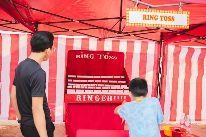 Colorful rings surround a set of upright pegs, ready for a fun game of Ring Toss at the carnival. Players aim to toss rings onto the pegs to score points and win prizes in this classic and entertaining carnival game